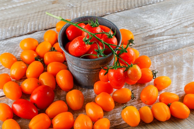 Tomatoes in a mini bucket on a wooden table. high angle view.