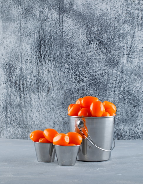 Free photo tomatoes in mini buckets. side view.