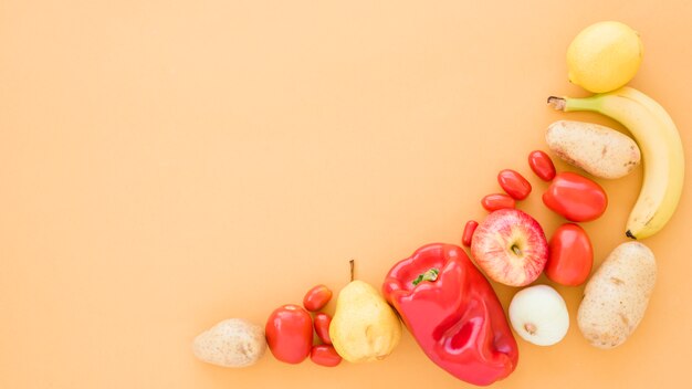 Tomatoes; potatoes; pears; banana; apple and lime on beige background