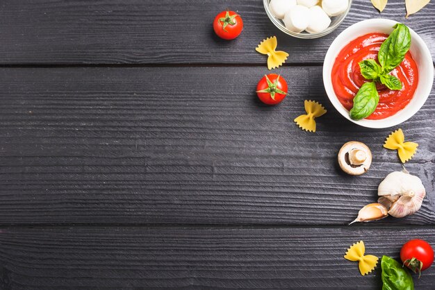 Tomatoes sauce with ingredients on black wooden plank