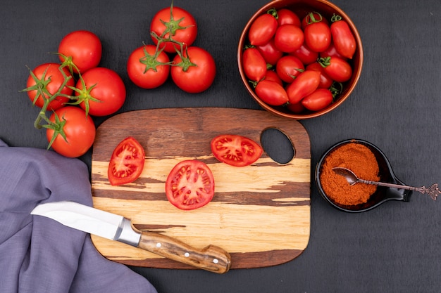 tomatoes top view concept with knife on cutting board on dark