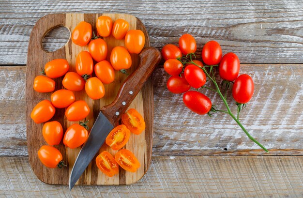 Tomatoes with knife flat lay on wooden and cutting board