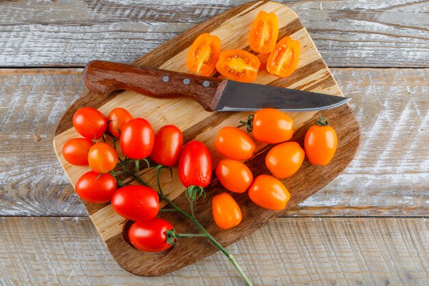 Tomatoes with knife on wooden and cutting board, flat lay.