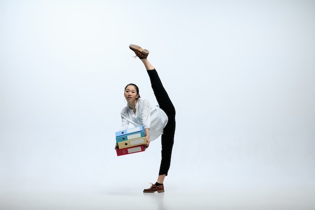 Foto gratuita troppi casi per la giornata. grave donna che lavora in ufficio, saltando e ballando in abiti casual o vestito isolato su sfondo bianco studio. business, start-up, concetto di lavoro open-space.