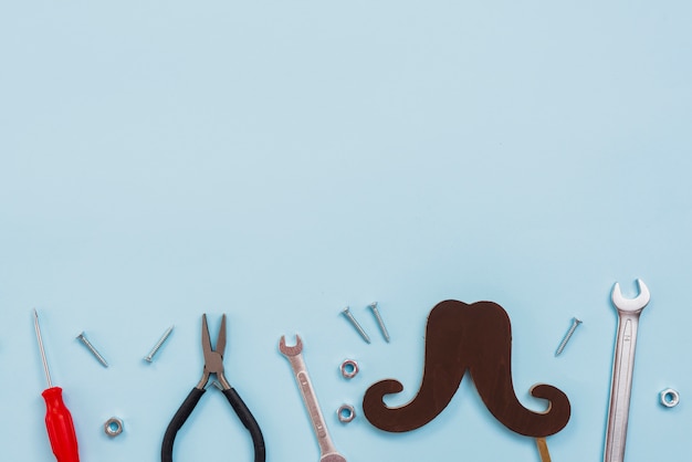 Tools with black paper mustache on table