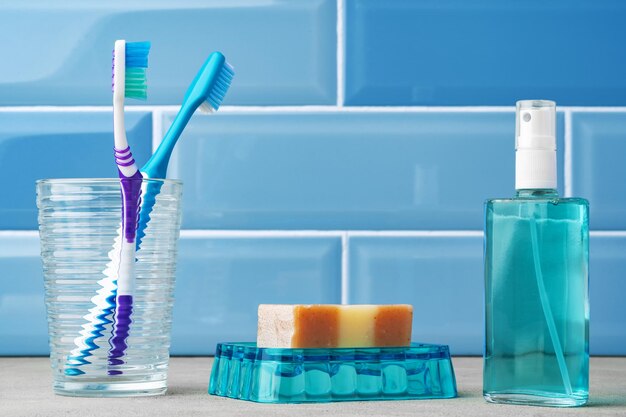 The toothbrushes in a glass in blue bathroom