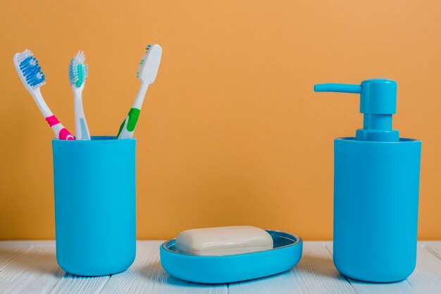 Toothbrushes soap and soap dispenser bottle on white desk against wall