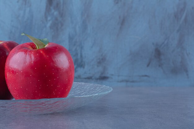 Toothsome apples on a glass plate on marble table.