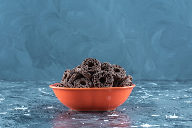 Toothsome chocolate coated corn ring in a bowl, on the marble background. 
