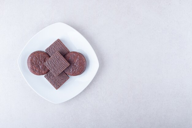 大理石のテーブルのプレートに、歯ごたえのあるチョコレートで覆われたクッキーとウエハース。