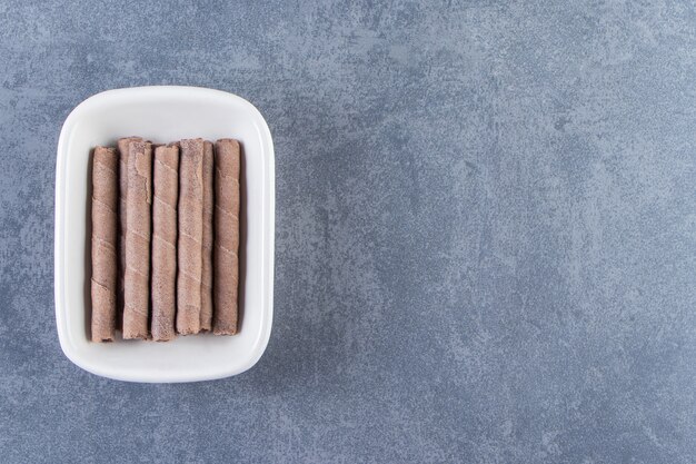 Toothsome chocolate wafer roll in a bowl , on the marble background.