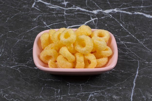 Toothsome corn rings in the pink plate, on the marble surface