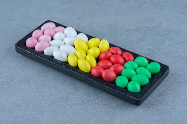 Toothsome gums in the wooden tray , on the marble table. 