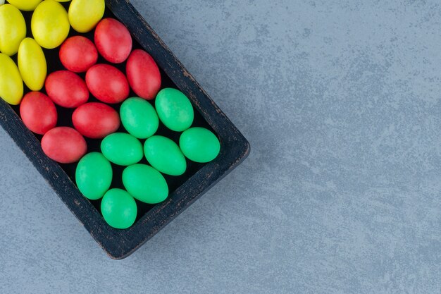 Toothsome gums in the wooden tray , on the marble table. 