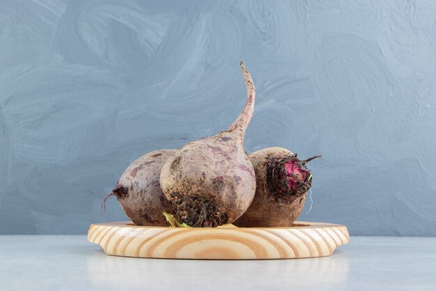 Toothsome radishes in the wooden plate , on the marble background.