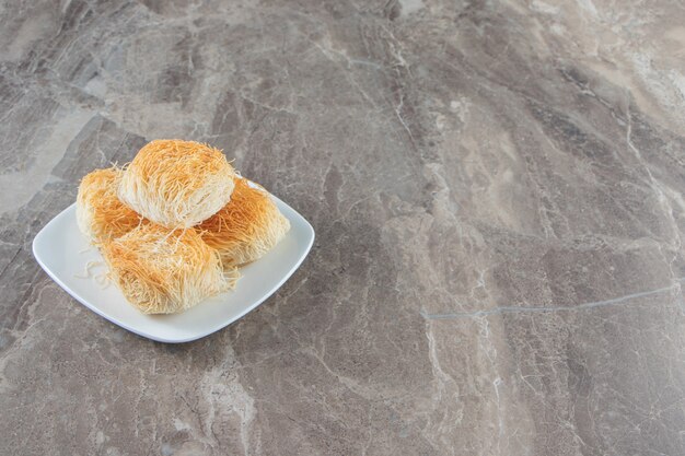 Toothsome Turkish dessert kadayif on a plate on blue.