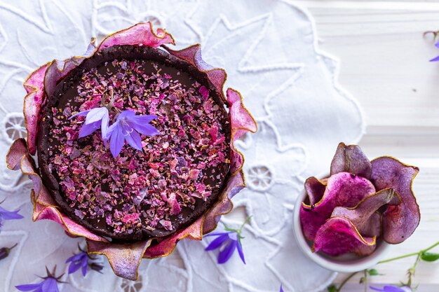 Top angle shot of a pear raw vegan purple cake with dehydrated pears on a white tabletop