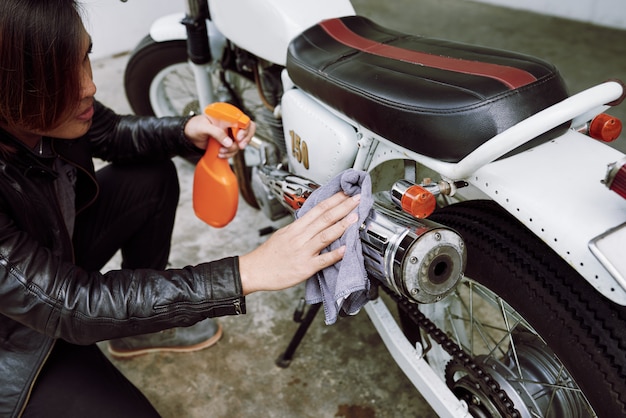 Top angle view of cropped biker polishing the pipe of his motorcycle