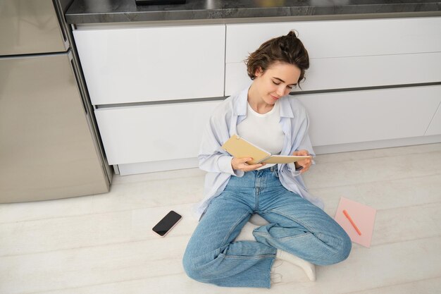 家で勉強している女子学生のトップアングルビュー日記を書いて床に座っている若い女性