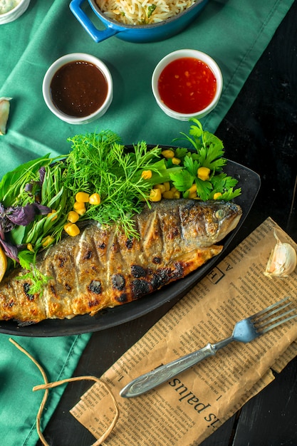 Top  baked sea bass served with fresh herbs and sauces on the table