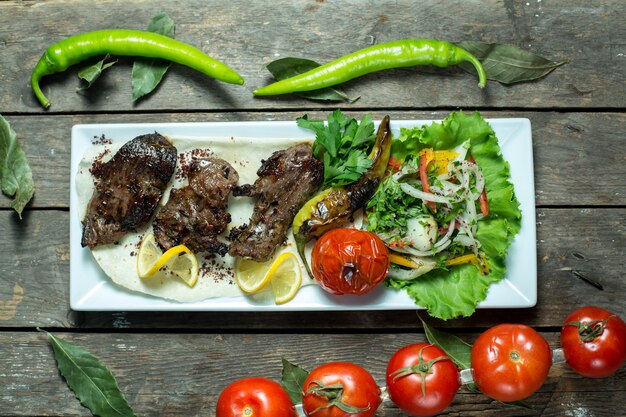 top  beef kebab served with onions grilled tomato and pepper on platter