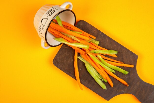 топ морковно-огуречные палочки на деревянной разделочной доске на желтом