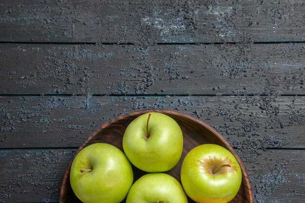 Top close-up view appetizing apples seven green-yellow apples in plate on the dark surface