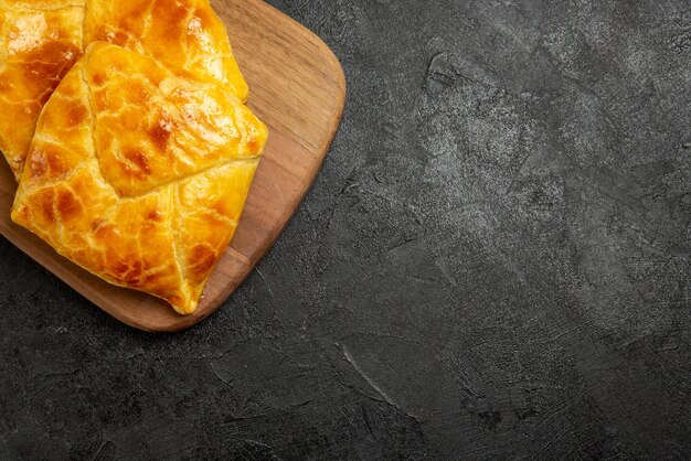 Top close-up view appetizing pies on the cutting board an appetizing pies on the left side of the table