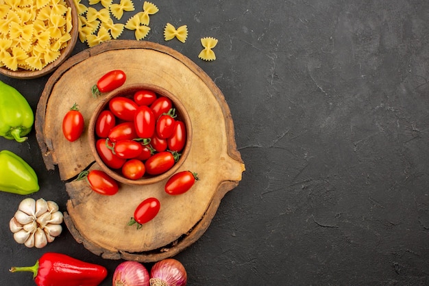 Vista ravvicinata dall'alto tagliere di verdure appetitose con una ciotola di pomodori e verdure appetitose sul tavolo nero