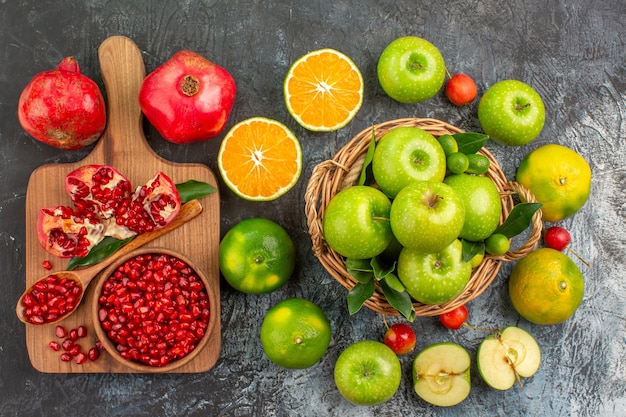 Top close-up view apples apples in the basket citrus fruits cherries board of pomegranate