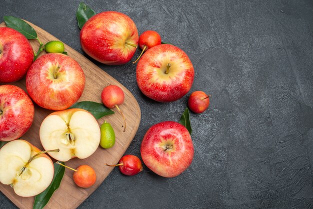 Top close-up view apples apples with leaves board with citrus fruits cherries and apples