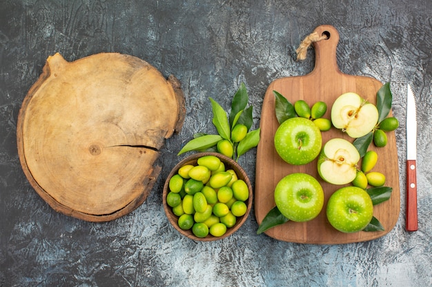 Free photo top close-up view apples apples with leaves knife bowl of citrus fruits the cutting board
