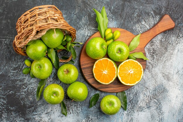 まな板の上に葉の柑橘系の果物とリンゴの上部のクローズアップビューリンゴのバスケット