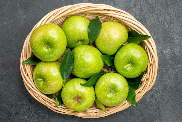 Top close-up view apples in the basket eight apples with green leaves in the wooden basket