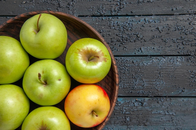 Бесплатное фото Сверху крупным планом яблоки на столе семь зелено-желто-красных яблок в миске на левой стороне темного стола
