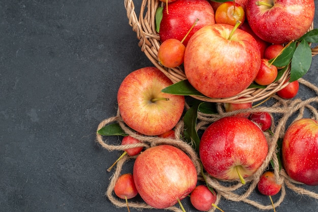 Top close-up view apples rope apples red-yellow cherries in the basket