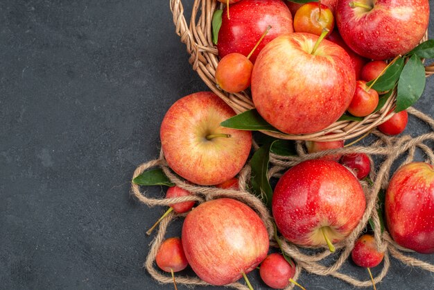 Вид сверху крупным планом яблоки веревка яблоки красно-желтые вишни в корзине