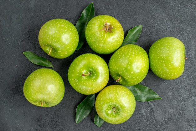 Бесплатное фото Сверху крупным планом яблоки семь зеленых яблок с листьями на черном столе