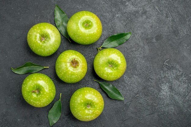暗いテーブルの上に葉を持つ食欲をそそる緑のリンゴの葉を持つ上部のクローズアップビューリンゴ