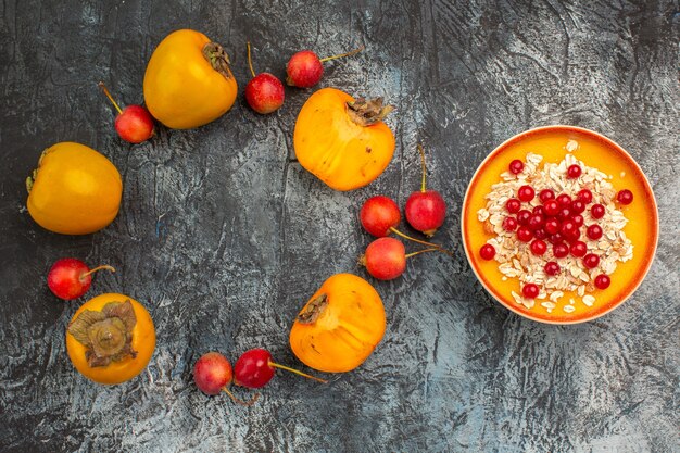 Top close-up view berries the appetizing cherry persimmons next to the bowl of red currants