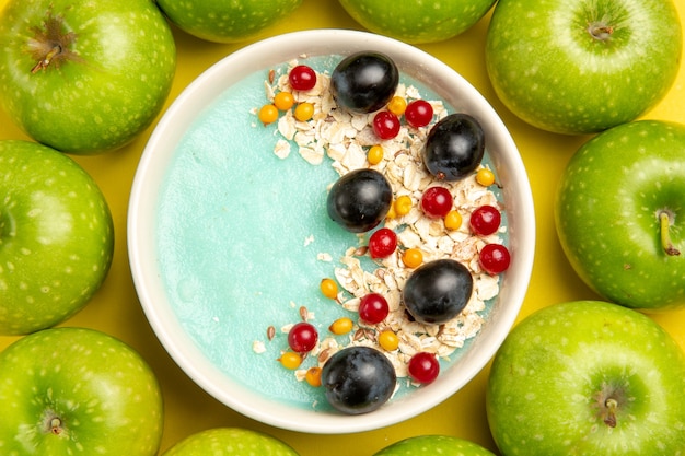 Top close-up view berries apples around black grapes red currants oatmeal in the bowl