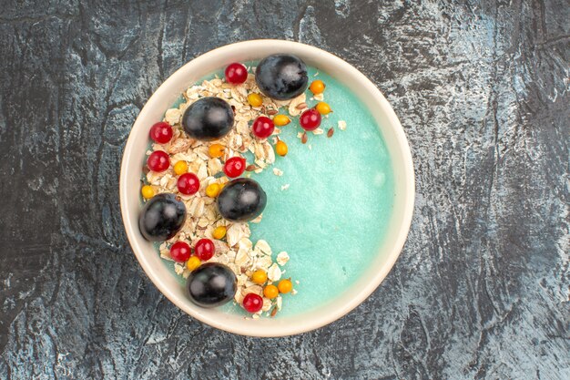 Top close-up view berries bowl of the appetizing red currants and grapes on the grey table