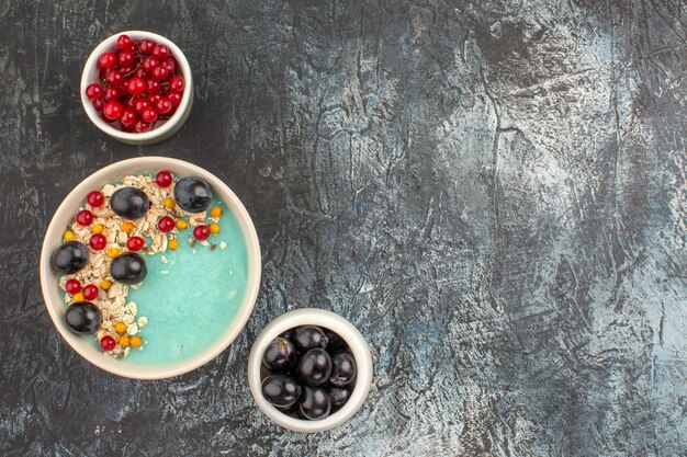 Top close-up view berries bowls of the appetizing berries and grapes on the grey table