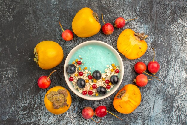 Top close-up view berries cherry next to the appetizing persimmons around bowl of berries