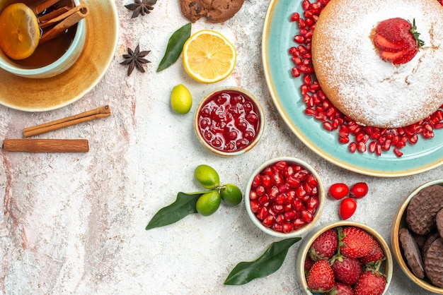 Top close-up view berries and cookies a cup of tea with lemon jam chocolate cookies the cake