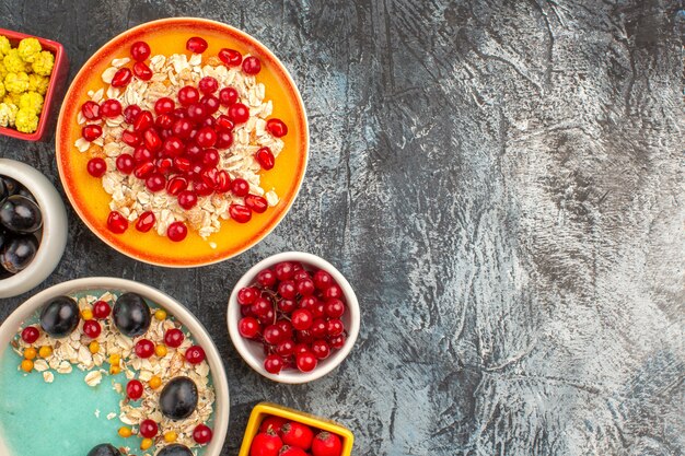 Top close-up view berries grapes cherries red currants candies oatmeal with pomegranate seeds