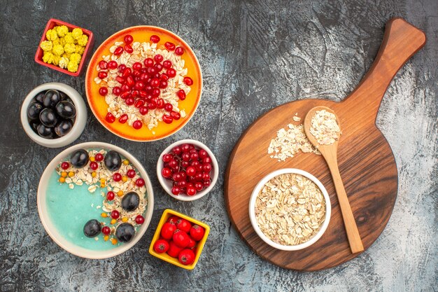 Top close-up view berries grapes cherries red currants pomegranate candies oatmeal on the board