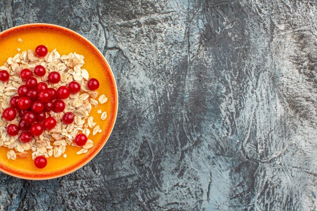 Top close-up view berries orange plate of the appetizing red currants on the grey table