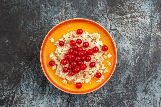 Top close-up view berries red currants on the orange plate on the grey table