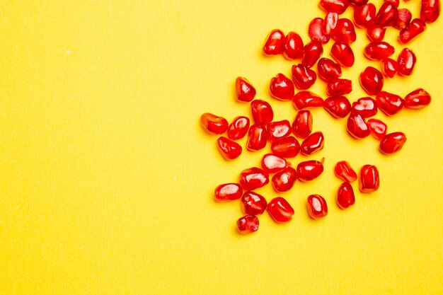 Top close-up view berries seeds of pomegranate on the yellow table